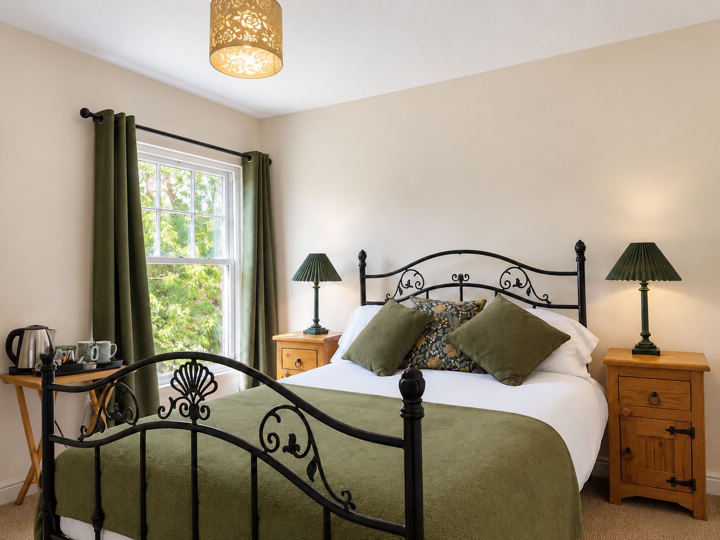 A bedroom with a bed, two bedside tables, a window with curtains, a lamp, and a nightstand.