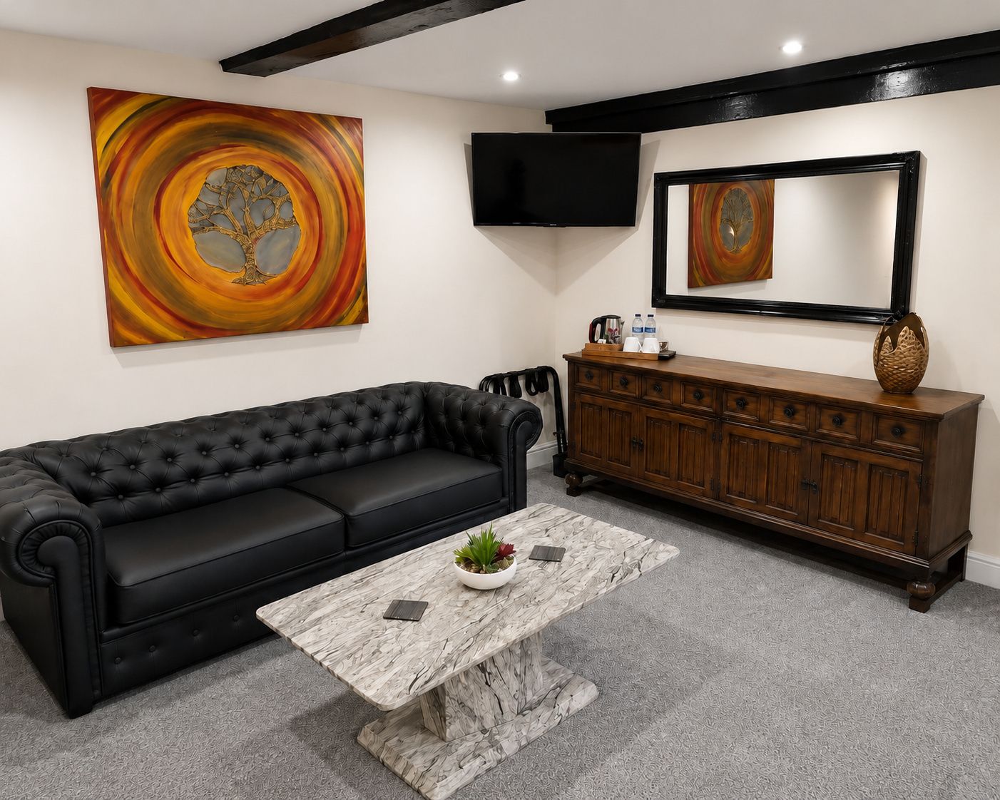 A living room with a black leather sofa, a marble coffee table, a wooden cabinet, and two abstract paintings.