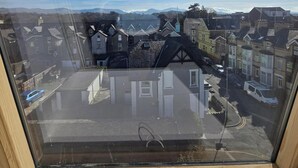 A view from a window with a clear sky, a street with parked cars, and buildings in the distance. - The Menai Hotel and Bar (Bangor)