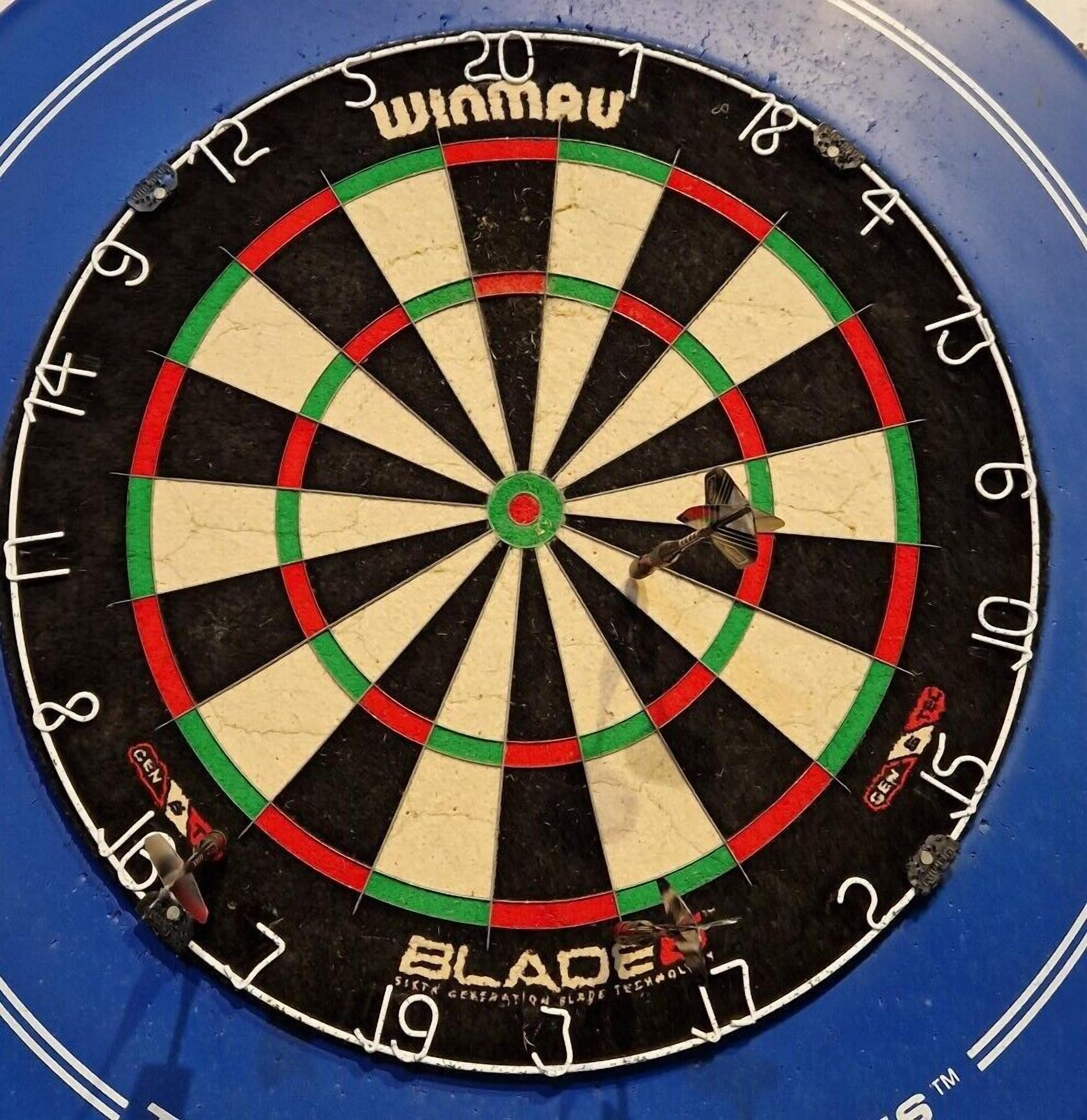 A dartboard with the brand name "WINMAU" and "BLADE" visible.