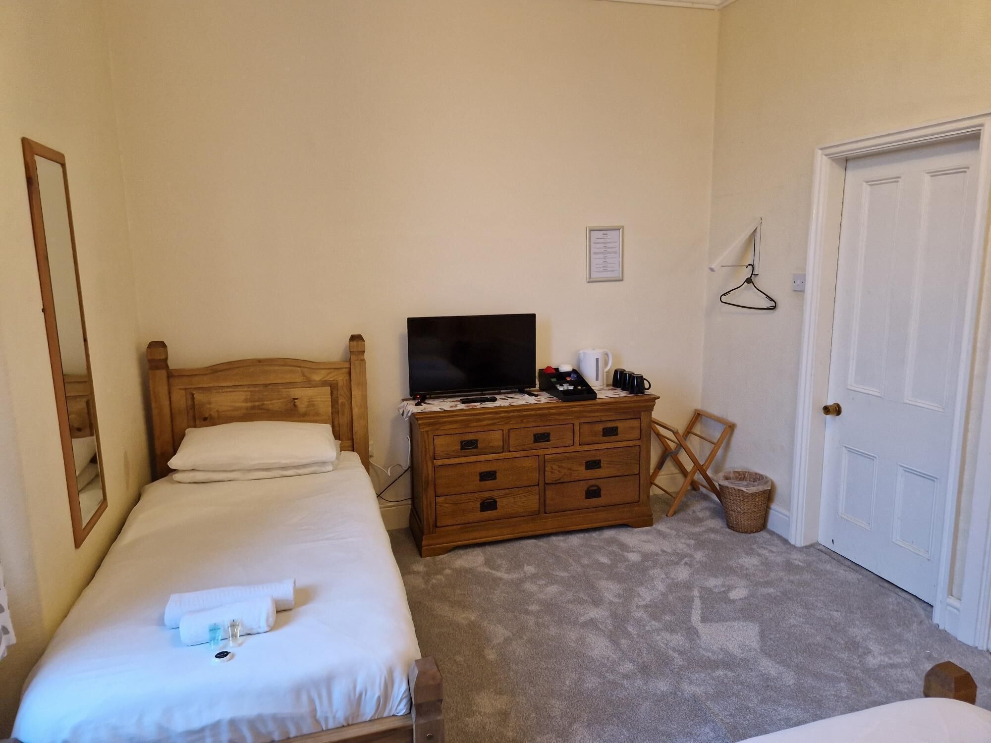 Un dormitorio con una cama de madera, un aparador, un televisor y una puerta.