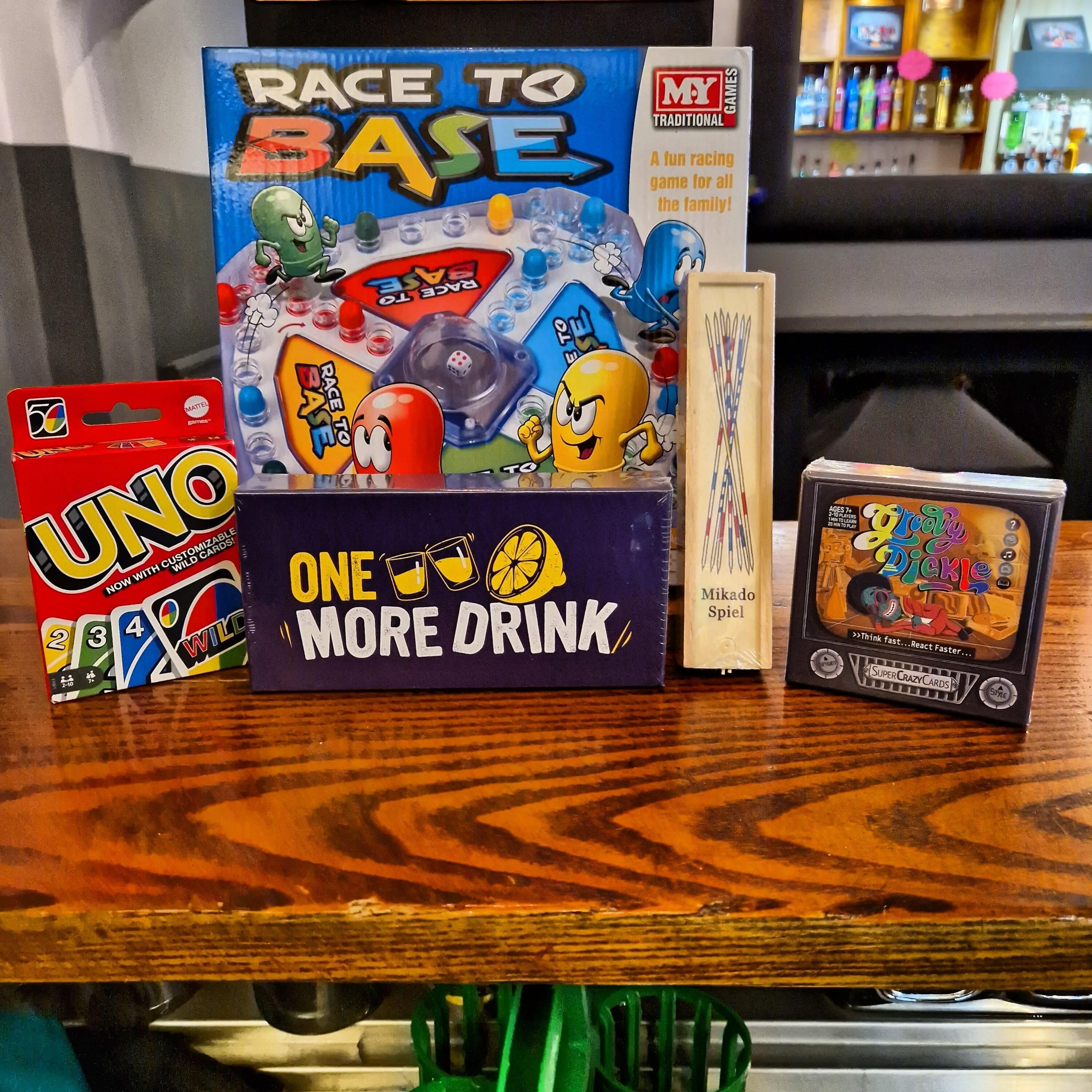 A table with various board games including UNO, Race to Base, and Crazy Pickle.