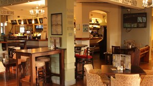 A bar area with tables and chairs, a counter with a sign that says "Please order food at the bar", and a wall with a sign that says "Please order food at the bar". - The Menai Hotel and Bar (Bangor)