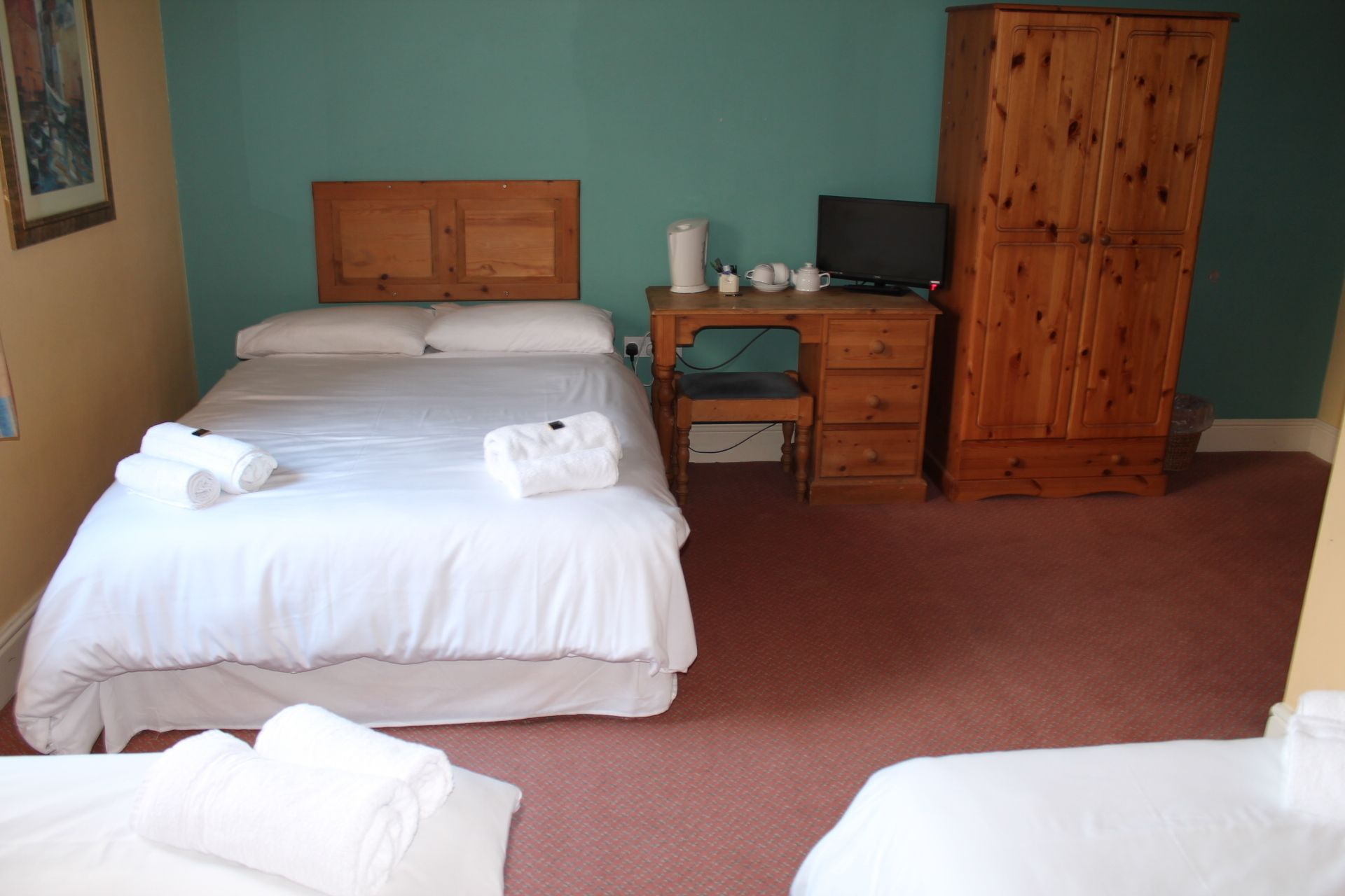 A hotel room with a bed, a desk with a computer, a wardrobe, and a chair.