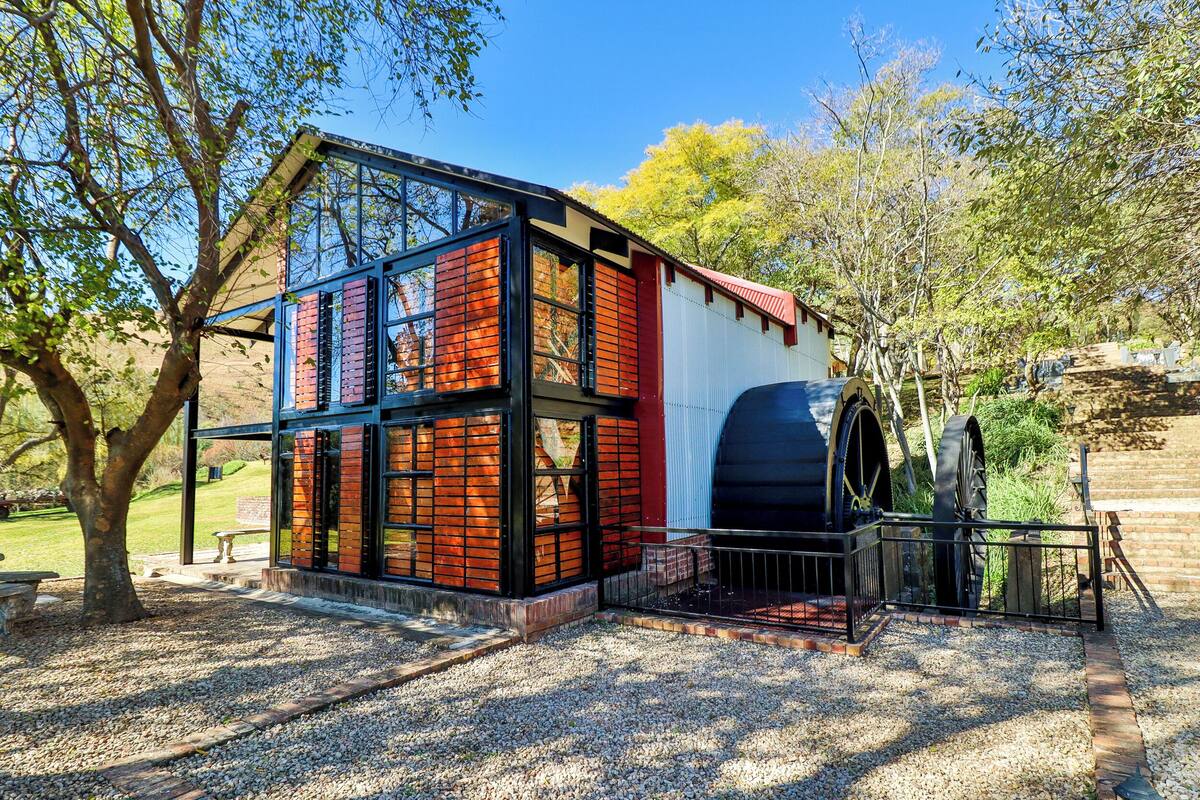 A building with large windows, a red roof, and a water wheel.