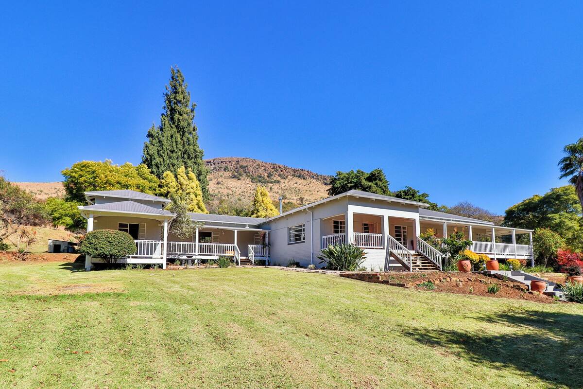A two-story house with a front porch, a covered patio, and a large lawn.