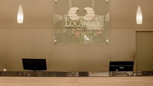 A reception desk with a glass sign reading 'Locanda Hotel' and two computer monitors. - Locanda Hotel (Novo Hamburgo)