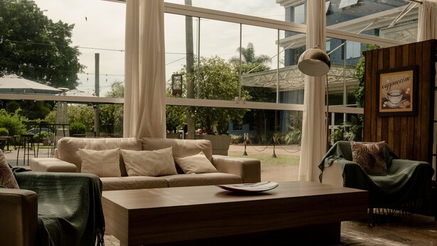 A modern living room with a sofa, armchairs, a coffee table, and large windows. - Locanda Hotel (Novo Hamburgo)