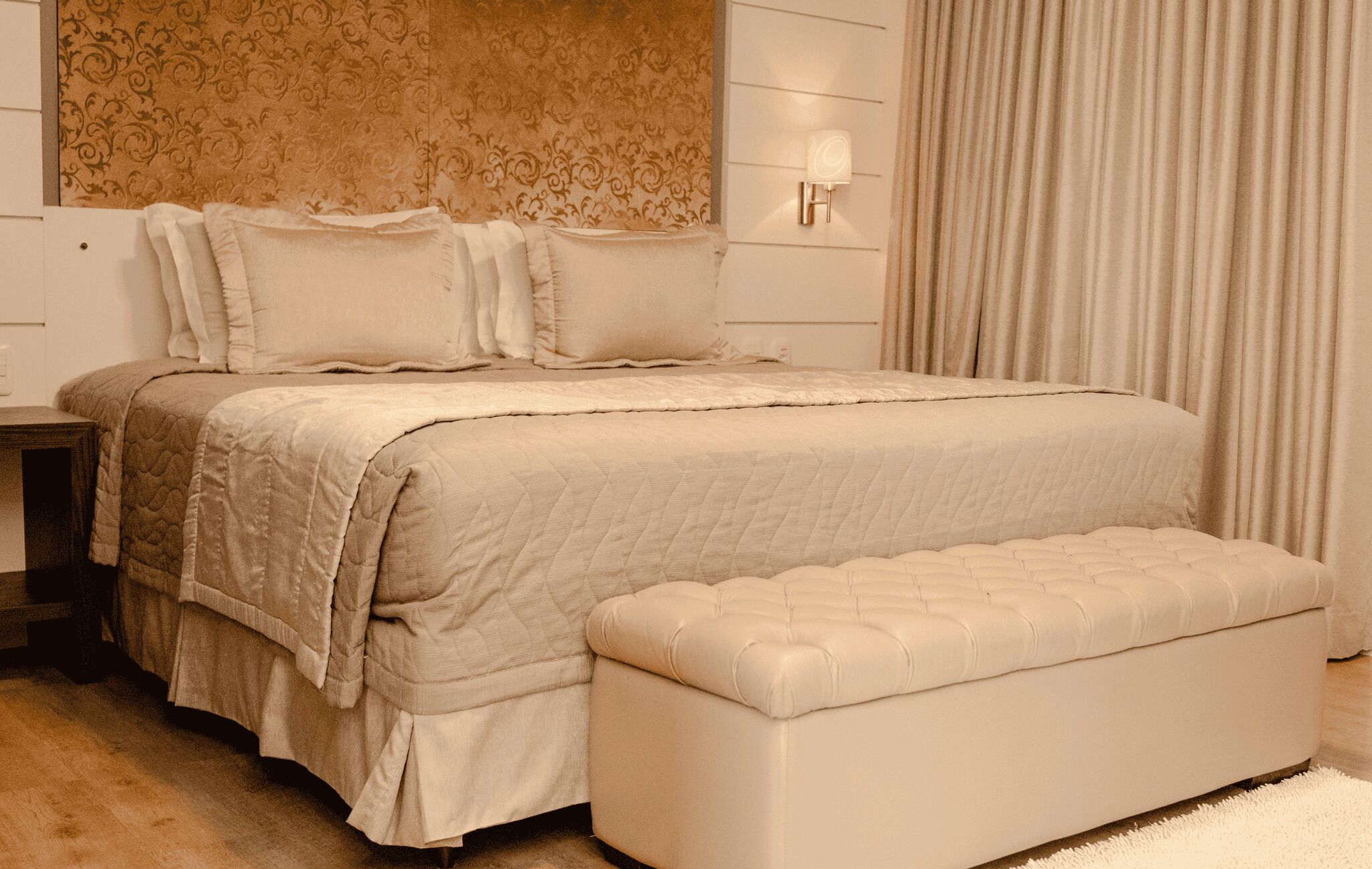 Een slaapkamer met een bed, nachtkastjes, een wandlamp en een raam met gordijnen.
