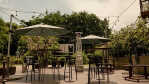 An outdoor patio with tables and chairs, string lights, and umbrellas. - Locanda Hotel (Novo Hamburgo)