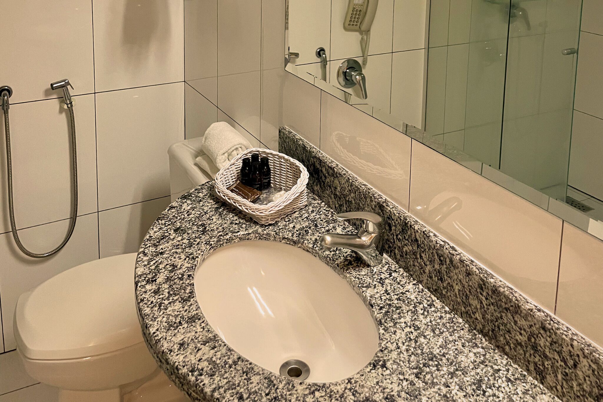 Une salle de bain avec un lavabo en granit, des toilettes, une douche et un miroir.