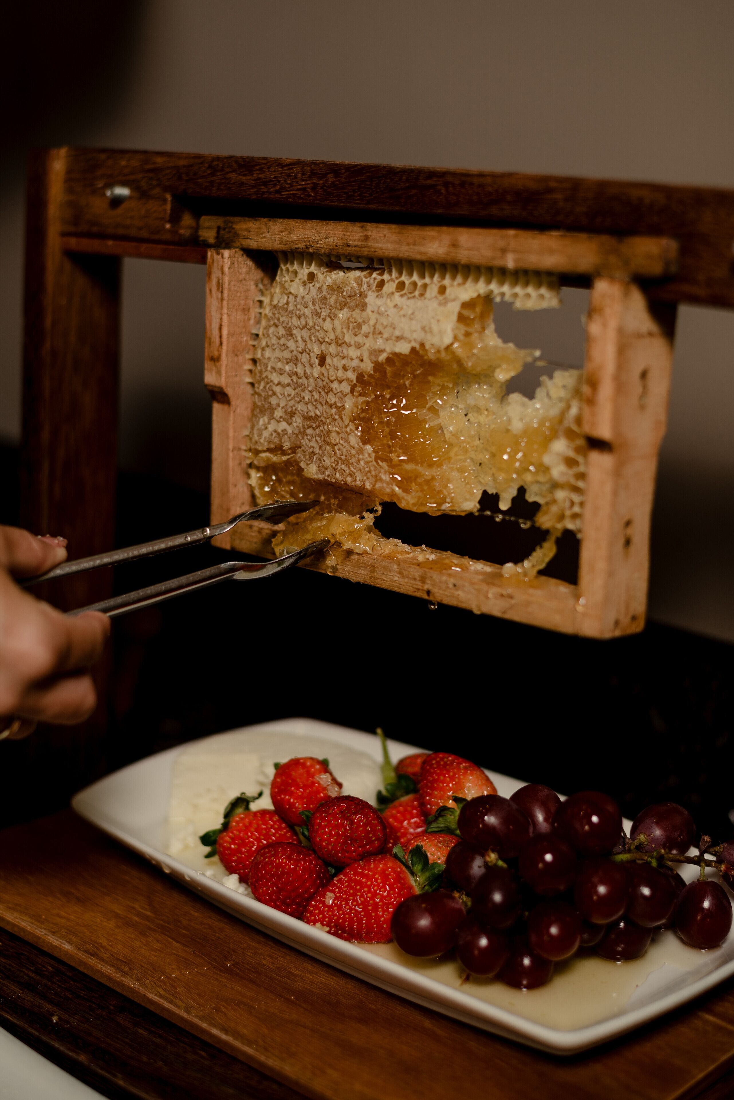 A wooden honeycomb frame with honeycomb and a knife.