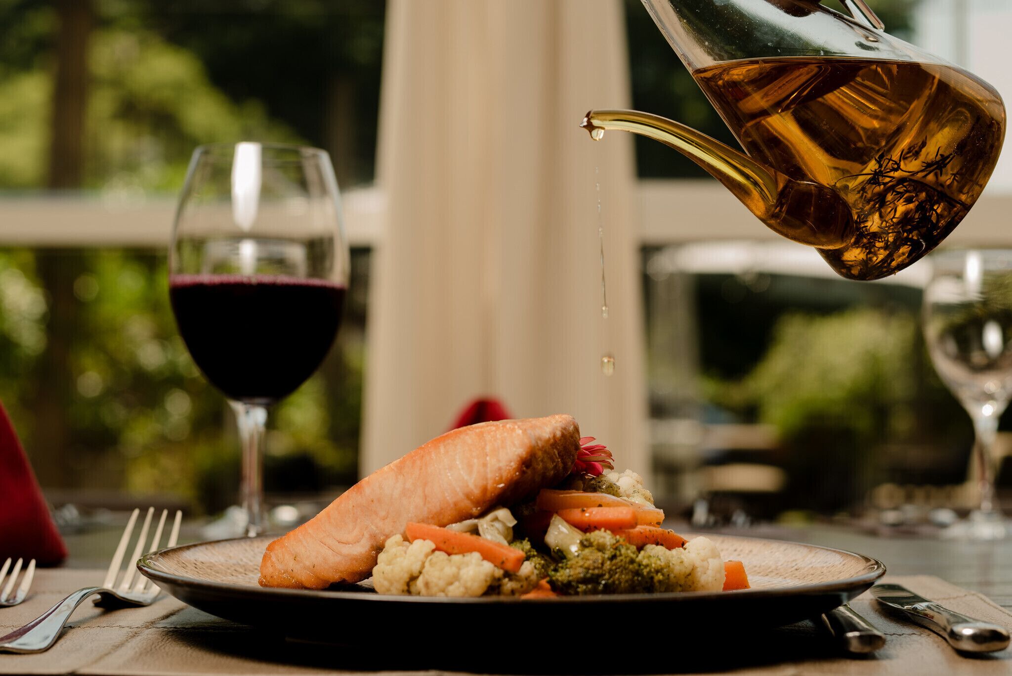 Une table à manger avec une assiette de nourriture, un verre de vin rouge et un verre de vin blanc.