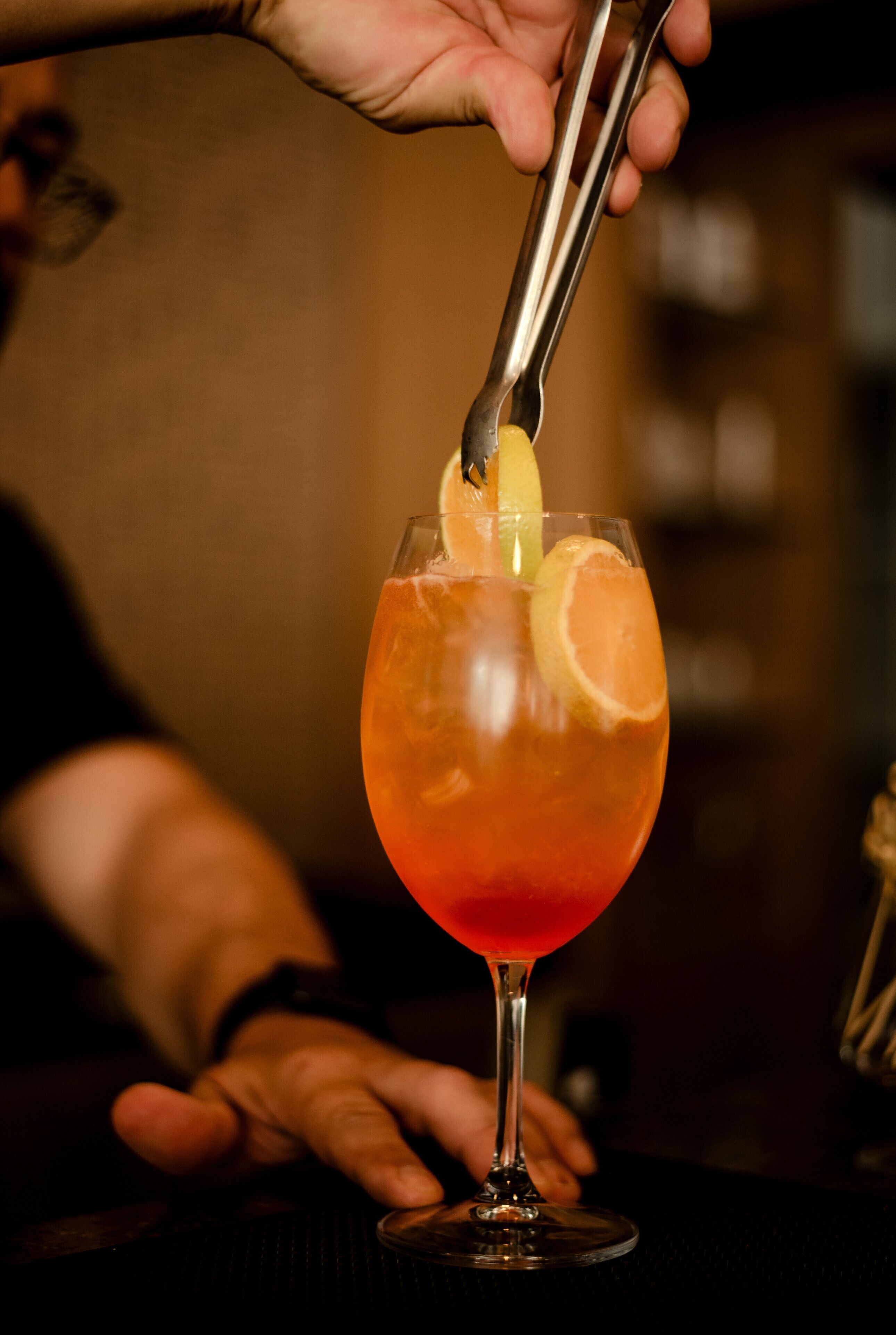 On est en train de décorer un cocktail avec une tranche de citron.