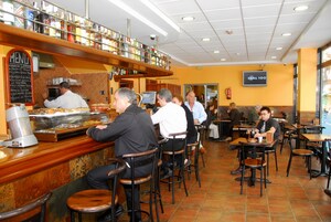 Un restaurante con mostrador, taburetes y mesas.