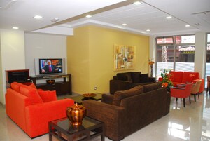 Una sala de estar moderna con sofás naranja y marrón, un televisor de pantalla plana y un florero con flores.