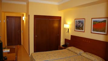 Camera d'albergo con un letto, una scrivania, una sedia, un comodino e due quadri appesi al muro.