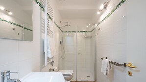 A modern bathroom with a white sink, toilet, and glass-enclosed shower.
