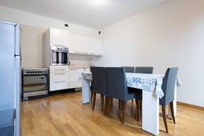 Compact kitchen with oven and microwave, adjacent to a dining space with table and four chairs.