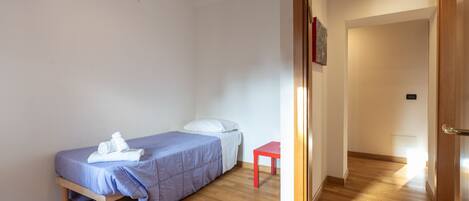 Une chambre à coucher avec un lit, une petite table et une porte donnant sur une autre pièce.