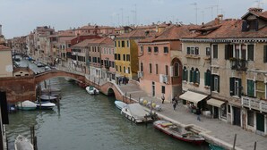 A canal with boats docked, buildings with balconies, and a pedestrian walkway.