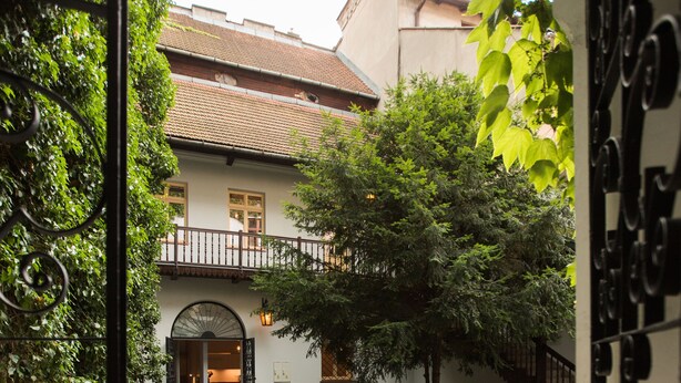 A courtyard with cobblestone paths, a building with a balcony, and a tree. - Sewa Apartamenty (Kraków)
