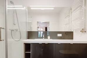 Un bagno moderno con box doccia in vetro, lavabo bianco e mobili scuri.