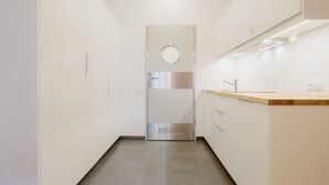 A modern kitchen with white cabinets, a stainless steel refrigerator, and a wooden countertop. - Sewa Apartamenty (Kraków)