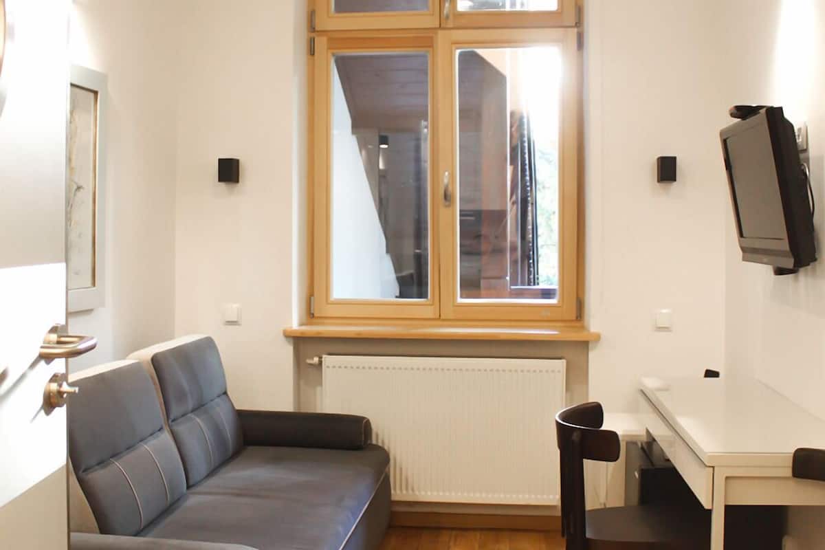Un espace de vie compact comprenant un canapé, une petite table à manger et un téléviseur fixé au mur.