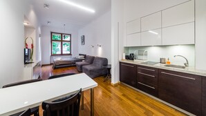A modern kitchen with dark cabinets, a white countertop, and a built-in sink. - Sewa Apartamenty (Kraków)