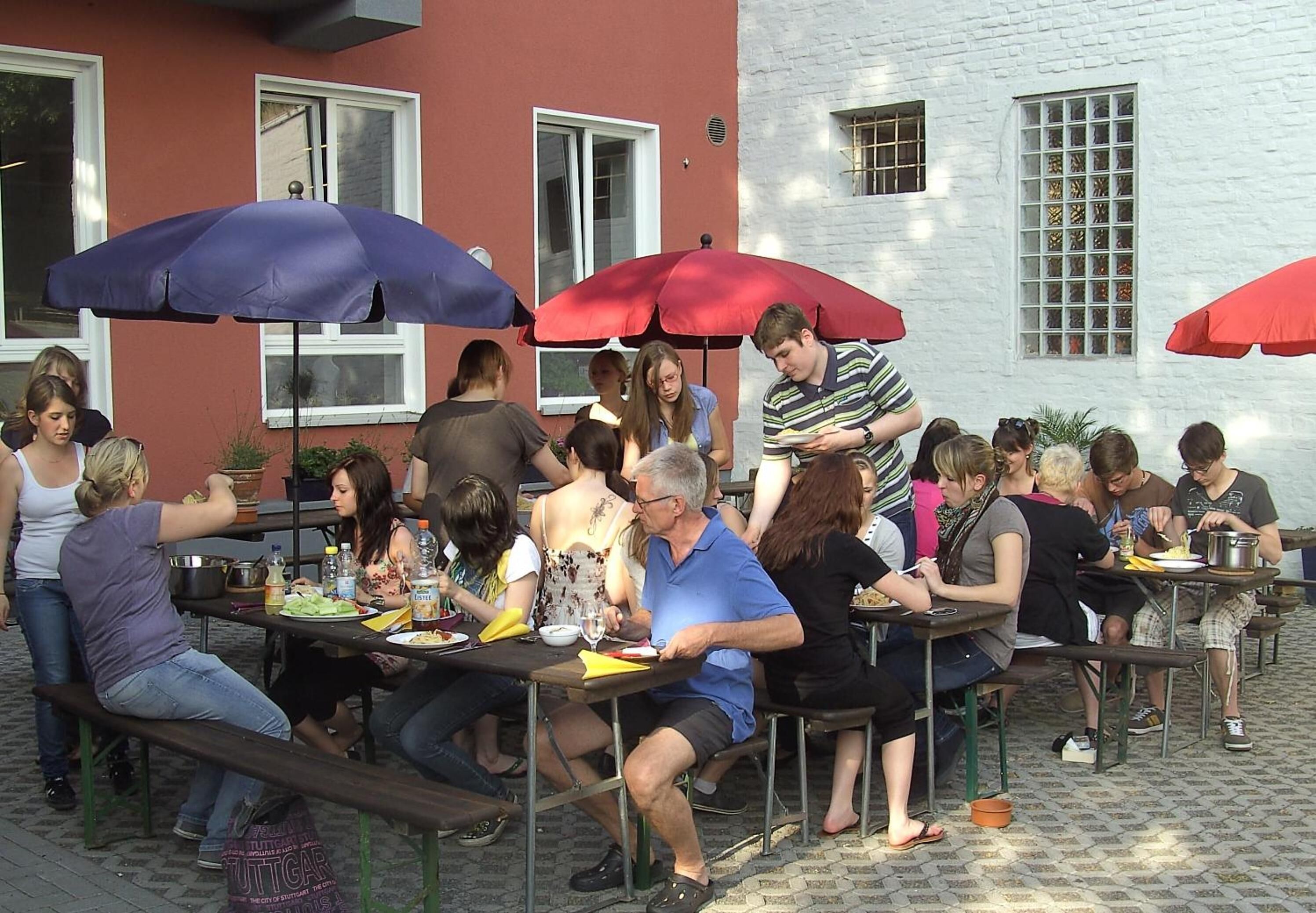A group of people dining outdoors at a restaurant with tables and umbrellas.