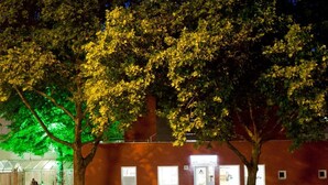 A building with a red facade, a gated entrance, and a well-lit entrance with a number '35' sign. - Pathpoint Cologne Backpacker Hostel (Cologne)