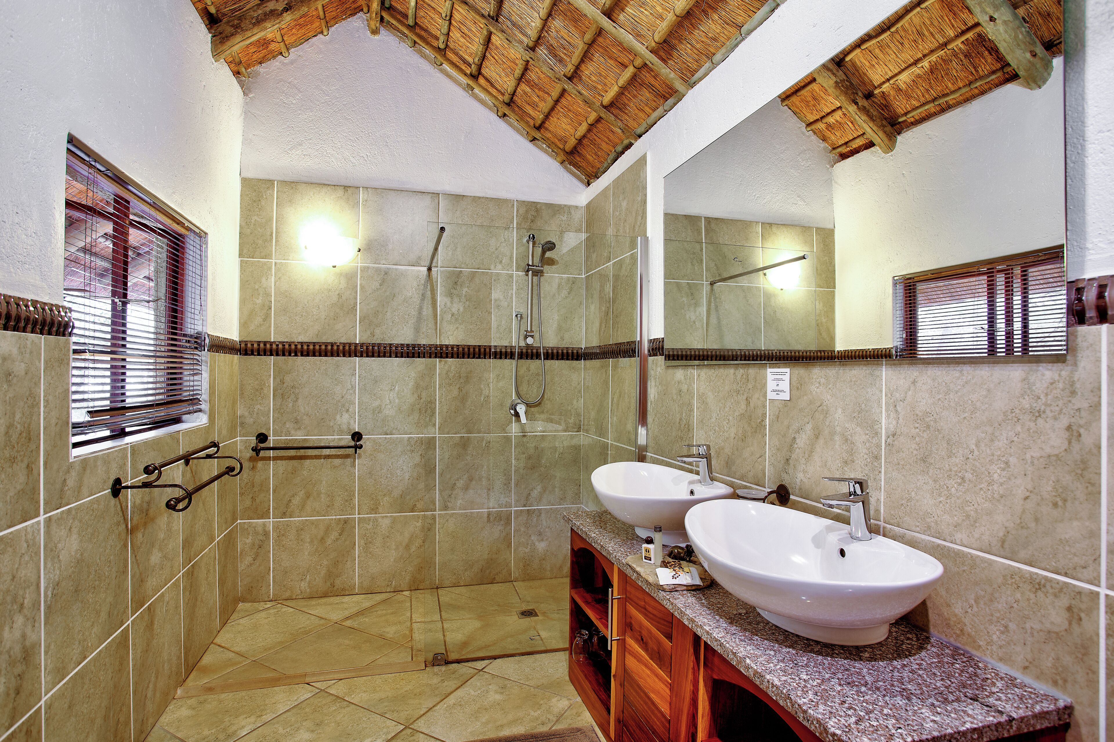 Un baño con dos lavamanos, ducha y techo de madera.