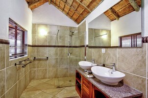 Un baño con dos lavamanos, ducha y techo de madera.