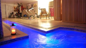 Un gimnasio en casa con equipo de ejercicio y una pequeña piscina.