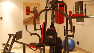 A home gym with a multi-functional exercise machine, a punching bag, and a blue exercise ball.