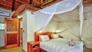 Una habitación con una cama bajo un dosel, cabecera de madera y una mesita de noche con un libro.