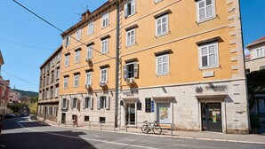 Un immeuble à plusieurs étages avec une façade jaune, une devanture visible avec une enseigne et un vélo garé à l’extérieur.