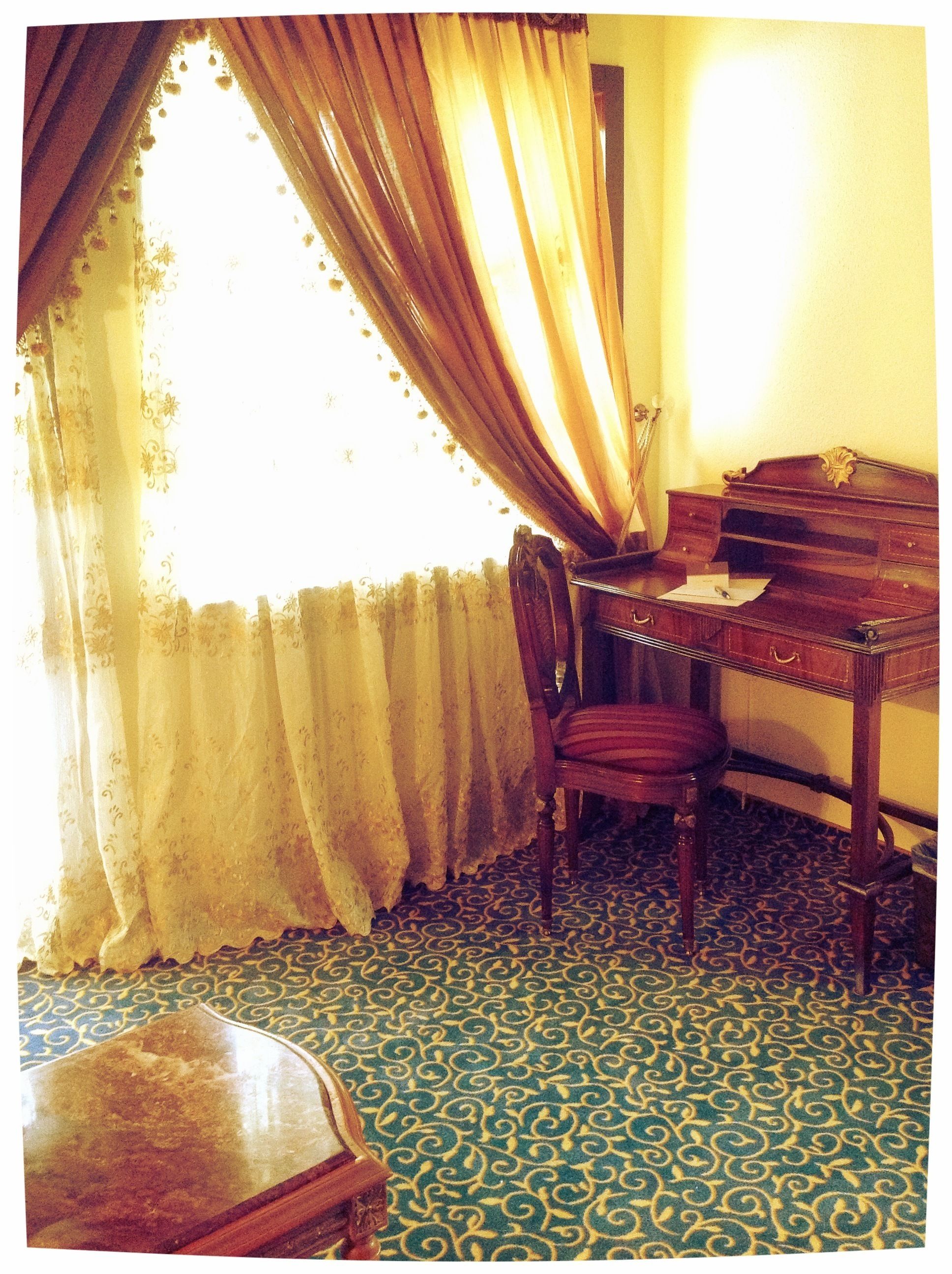 A room with a piano, a chair, and a patterned carpet.