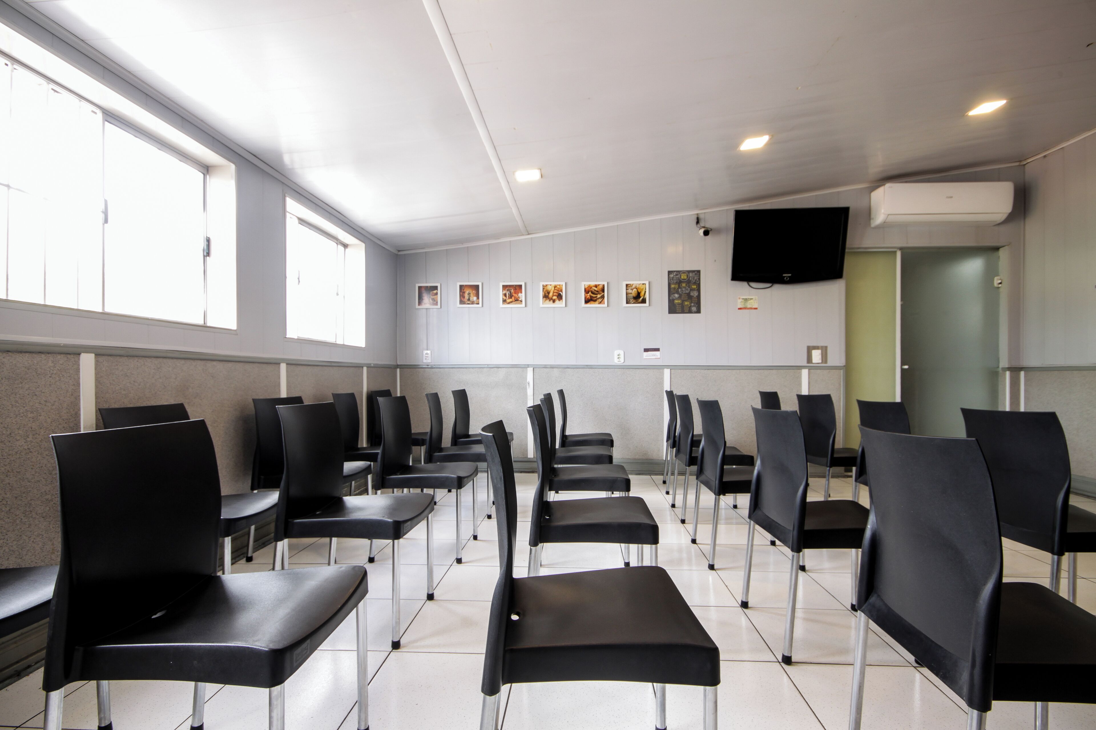 A waiting area with rows of black chairs and a flat-screen TV mounted on the wall.