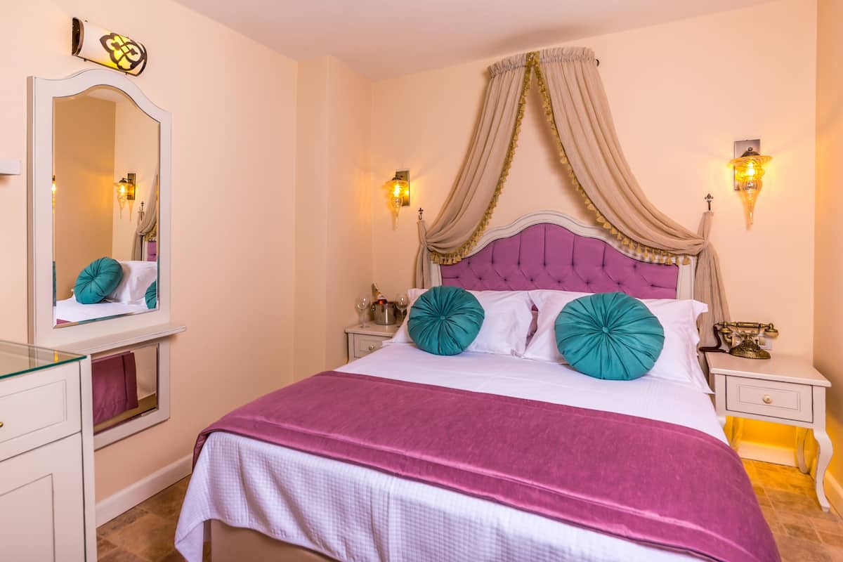 A bedroom with a bed, a vanity with a mirror, and bedside lamps.