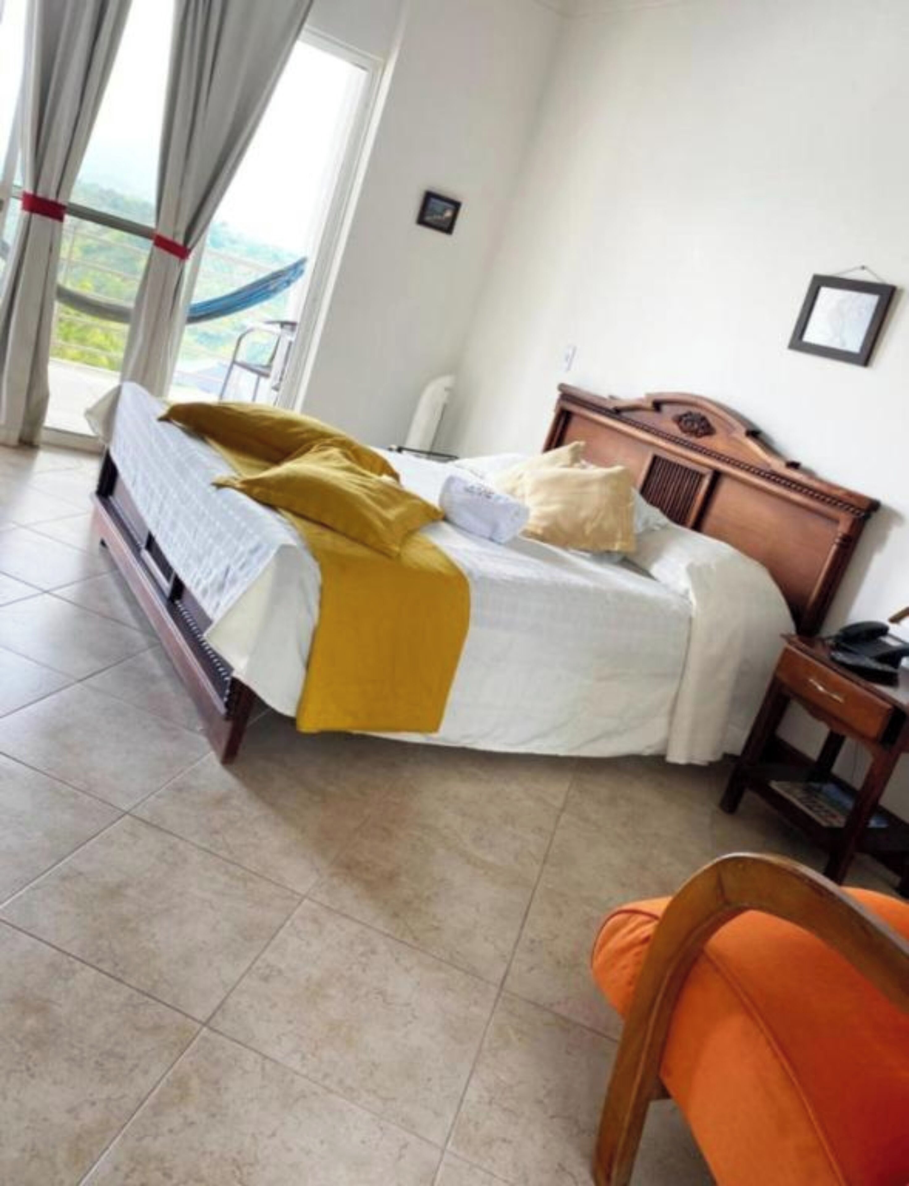 Une chambre à coucher comprenant un lit, une chaise, une table de chevet et une vue sur l’extérieur par une fenêtre.