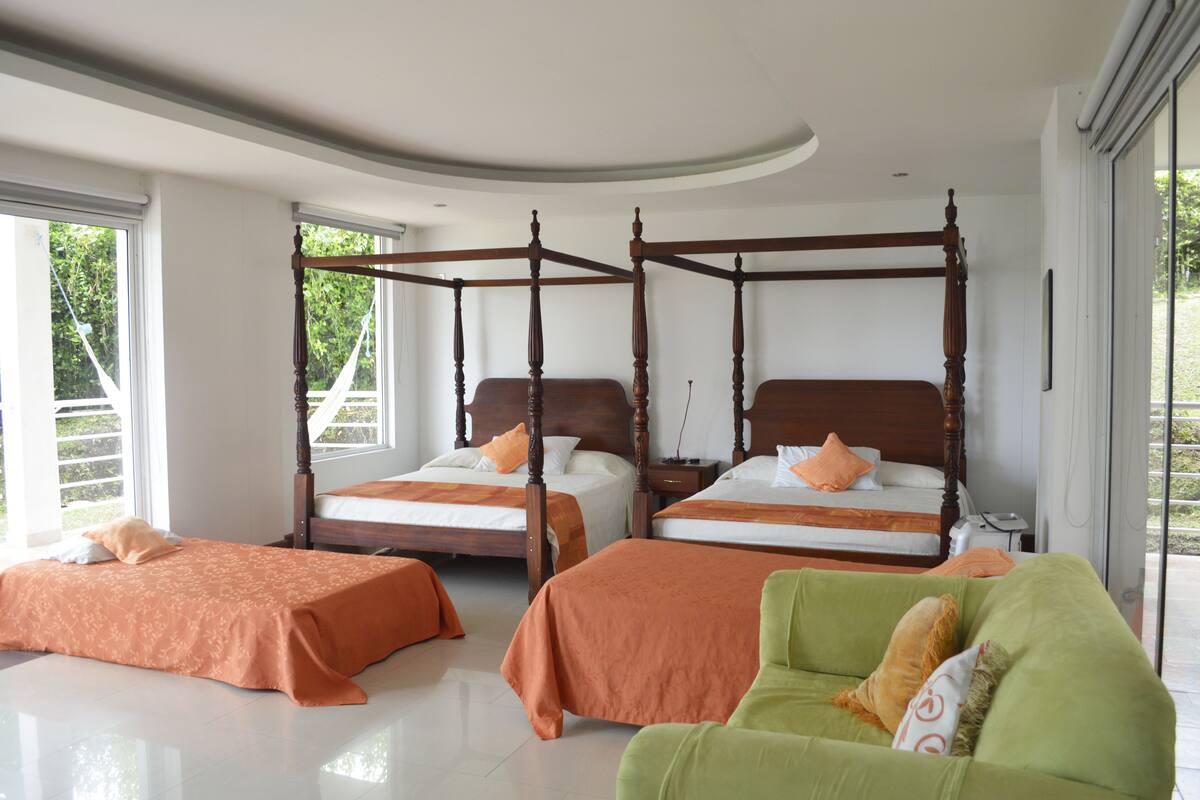 Un dormitorio con dos camas, un sofá verde y vistas al exterior.