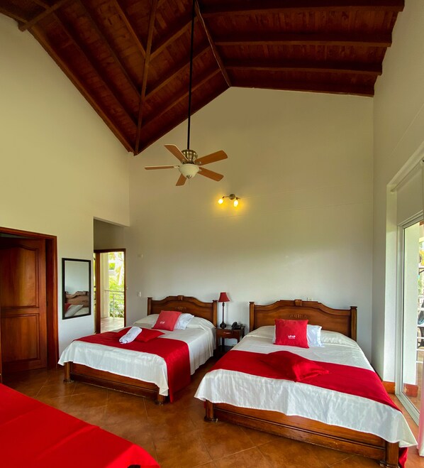 A hotel room with two beds, a ceiling fan, and a view of the outdoors.