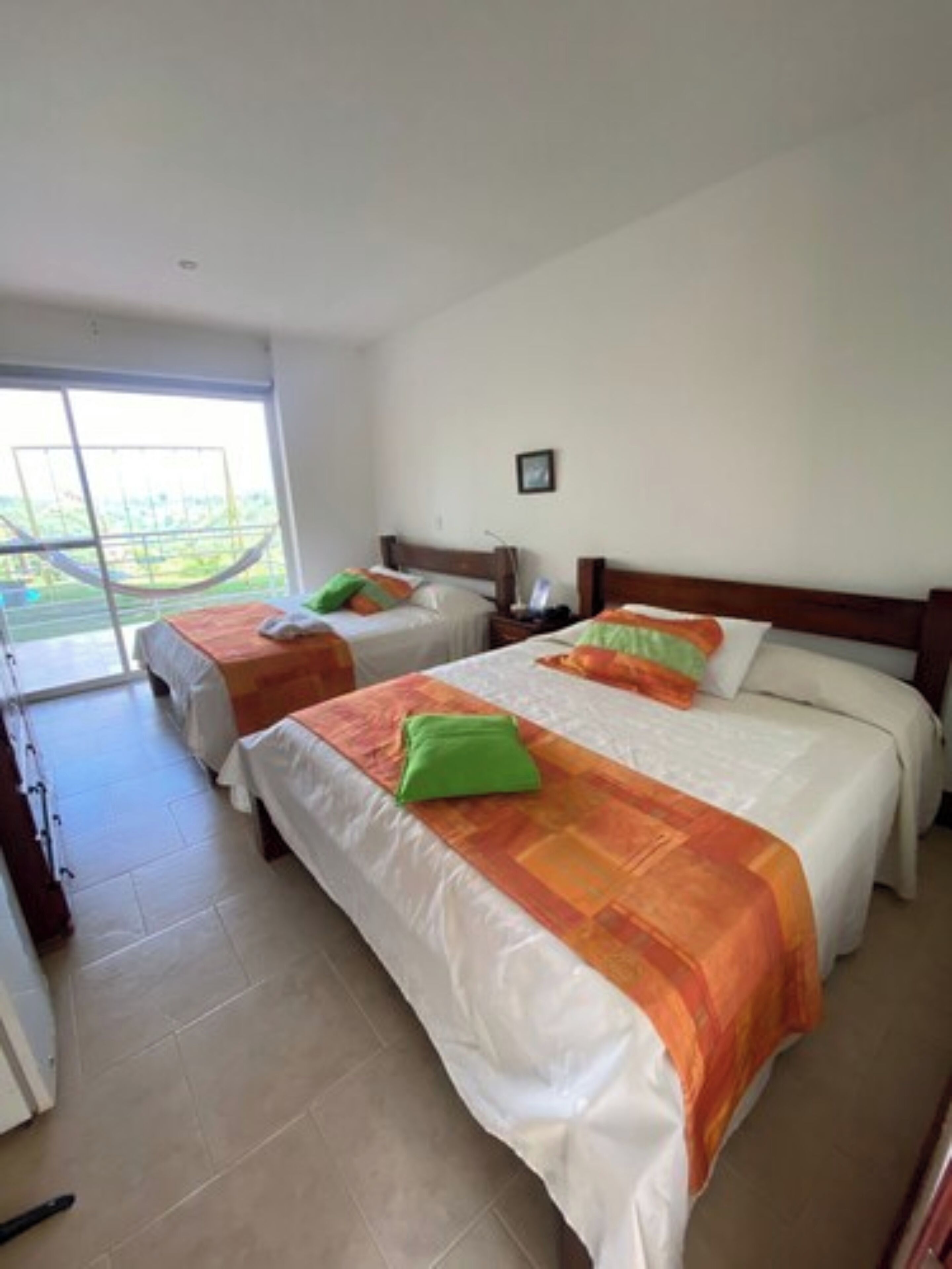 Una habitación de hotel con dos camas, un ventanal grande y vistas al exterior.