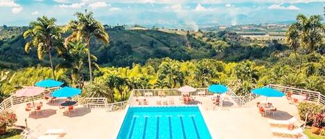 A swimming pool with a view of a hilly landscape and palm trees.