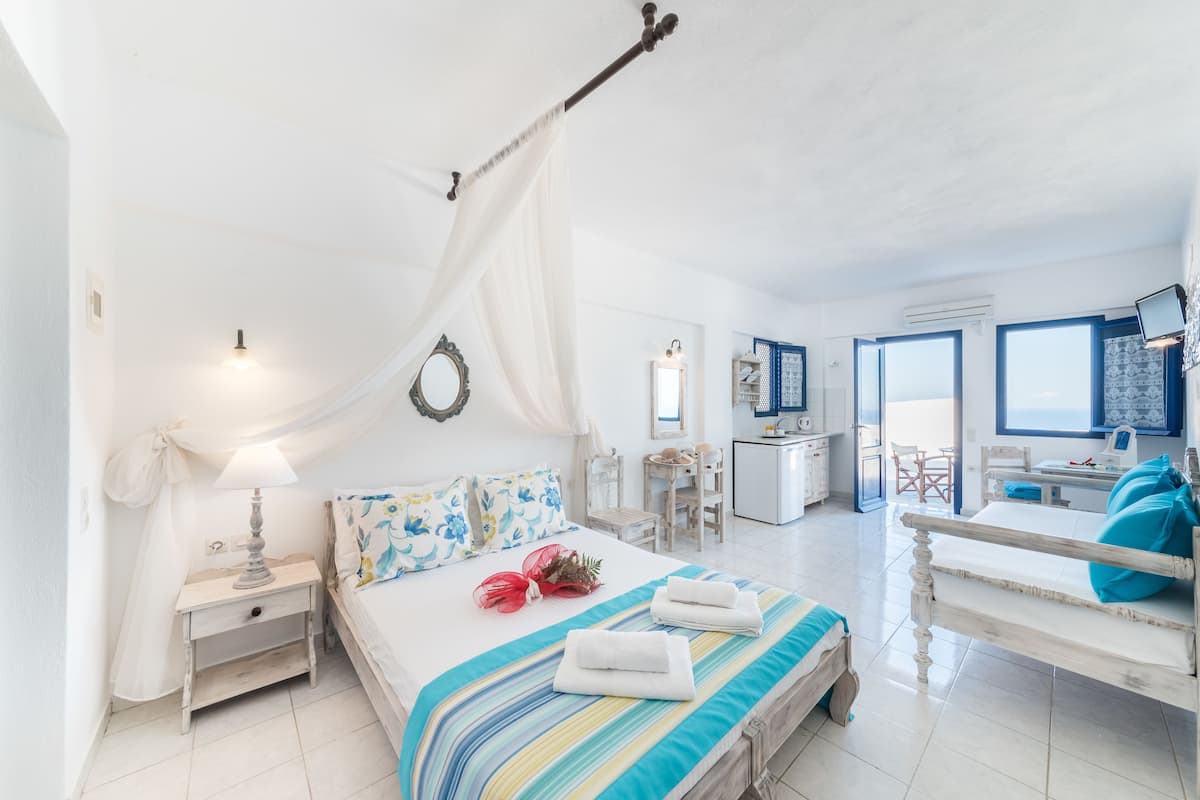 Ein Schlafzimmer mit Bett, Nachttisch, Lampe und Blick ins Badezimmer.