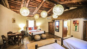 Una habitación con muebles de madera, una cama, una mesa de comedor y lámparas esféricas colgantes.