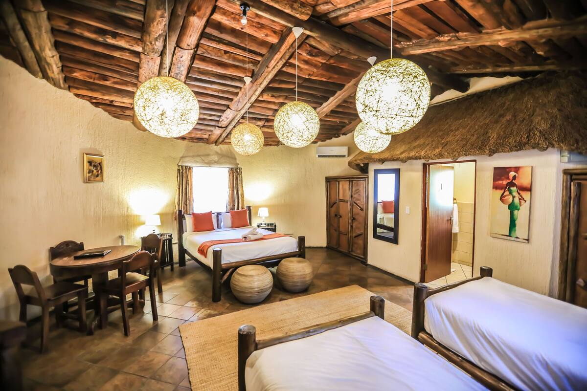 A room with wooden furniture, a bed, a dining table, and hanging spherical light fixtures.