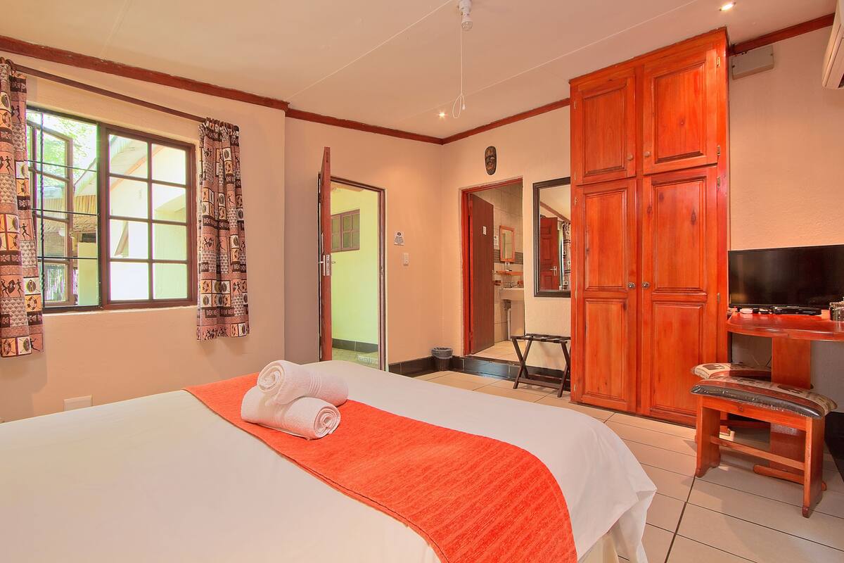 A hotel room with a large bed, a television, and a wardrobe.
